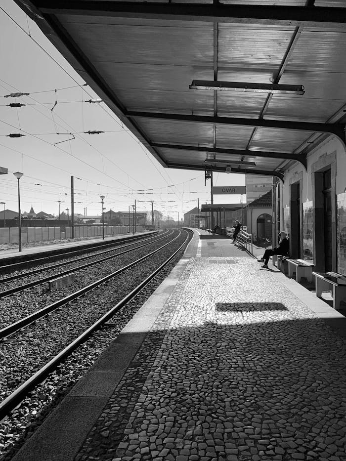 Quiet train station platform with sunlight and shadows, creating a vintage feel.